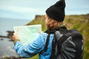 Shot of a young man looking at a map for directions outdoors on a group vacation