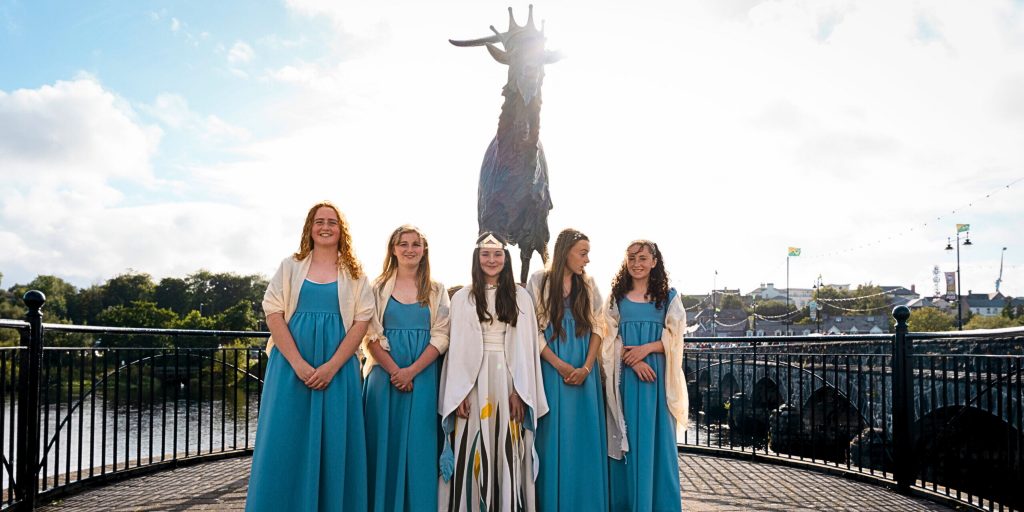 Line of girls in front of statue of Puck