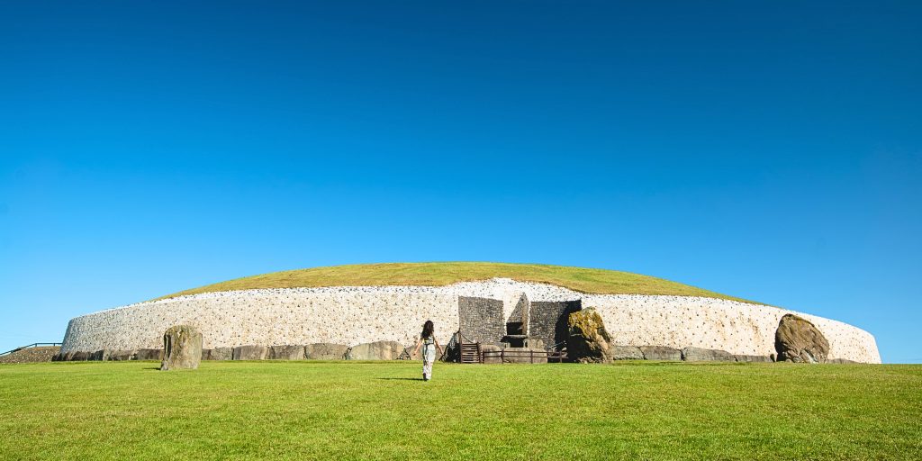 Woman walking towards large passage tomb